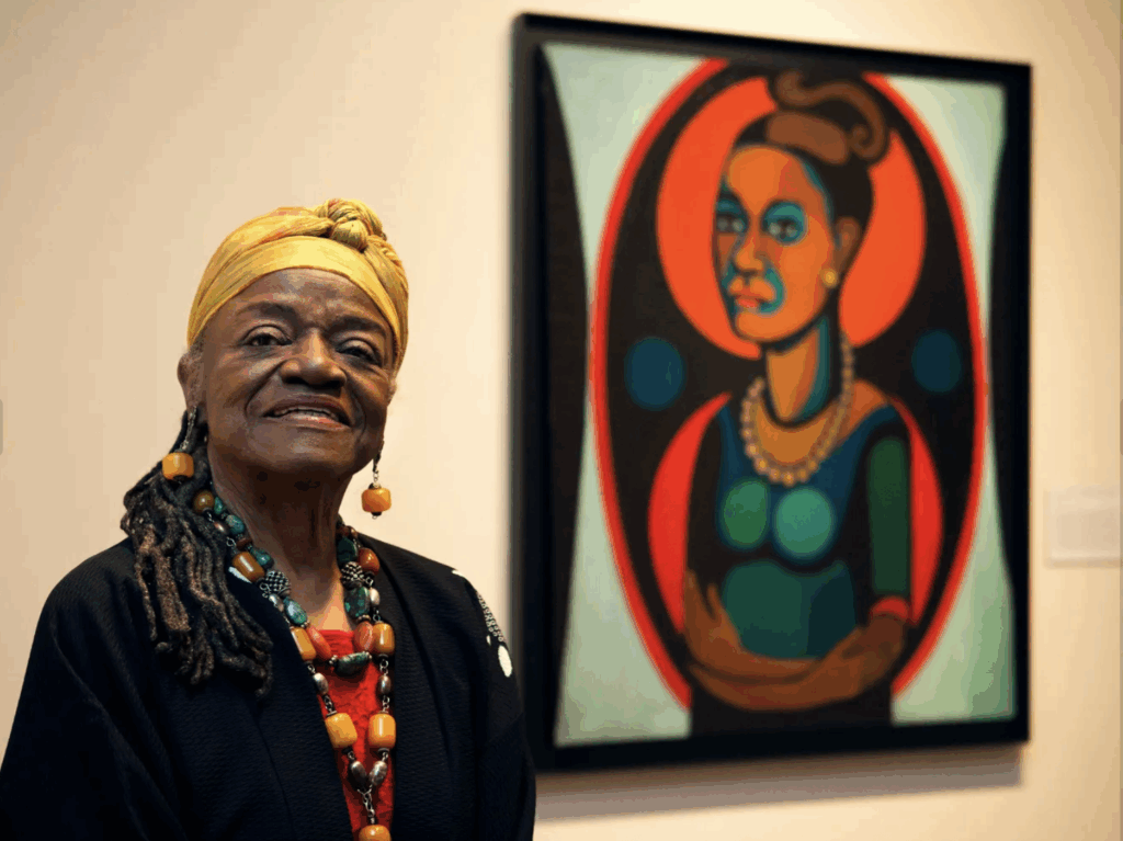 Faith Ringgold standing with quilt